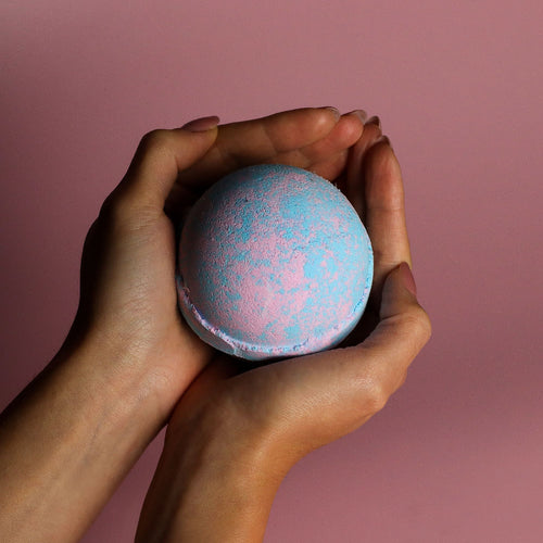 hands holding a blue and pink bath bomb