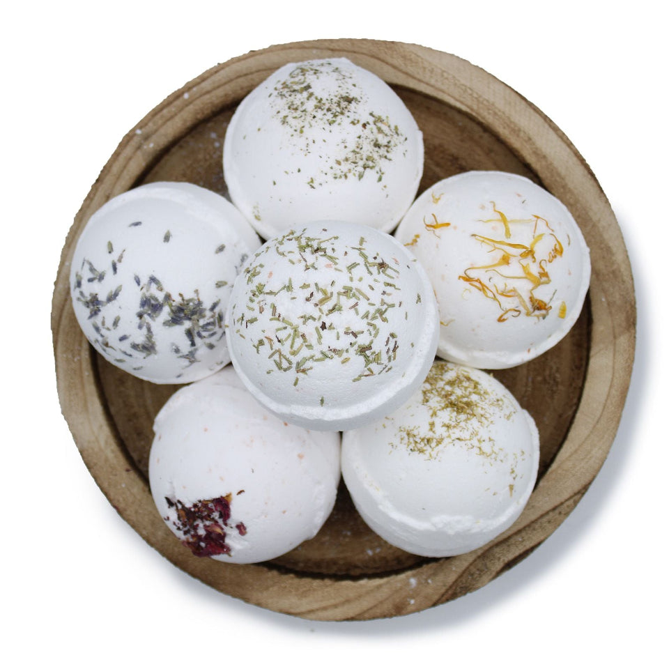 White bath bombs with visible ingredients in a wooden bowl on a white background
